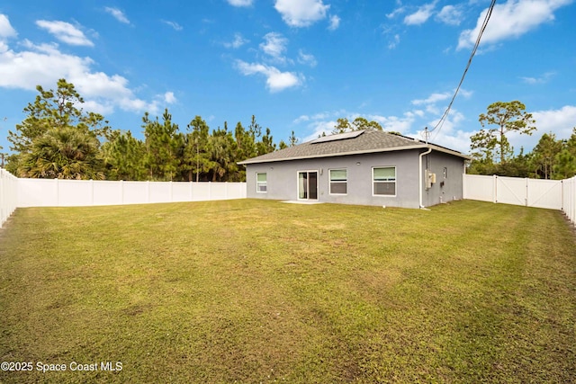 2840 Fontainebleau Ave SE, Palm Bay, FL 32909 - back of property with roof mounted solar panels, stucco siding, a fenced backyard, and a shingled roof