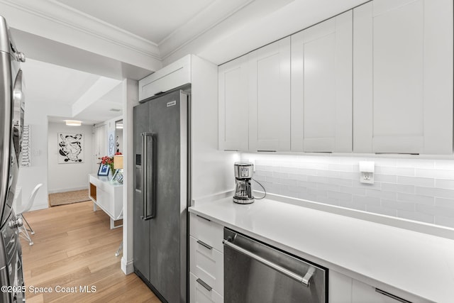 2100 N Atlantic Ave Unit 1110, Cocoa Beach, FL 32931 - kitchen with stainless steel appliances, ornamental molding, light wood-style floors, light countertops, and tasteful backsplash