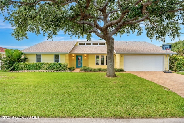 33 Yawl Dr, Cocoa Beach, FL 32931 - mid-century modern home with an attached garage, decorative driveway, a front lawn, and a shingled roof