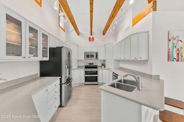 33 Yawl Dr, Cocoa Beach, FL 32931 - kitchen featuring appliances with stainless steel finishes, a peninsula, beam ceiling, light countertops, and light wood-style floors