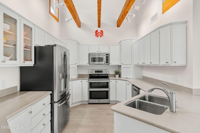 33 Yawl Dr, Cocoa Beach, FL 32931 - kitchen with appliances with stainless steel finishes, high vaulted ceiling, beamed ceiling, light wood-style flooring, and white cabinets
