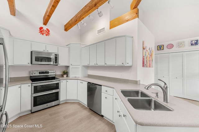 33 Yawl Dr, Cocoa Beach, FL 32931 - kitchen with appliances with stainless steel finishes, a peninsula, beamed ceiling, light countertops, and high vaulted ceiling