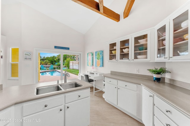 33 Yawl Dr, Cocoa Beach, FL 32931 - kitchen featuring high vaulted ceiling, white cabinetry, glass insert cabinets, light countertops, and light wood finished floors
