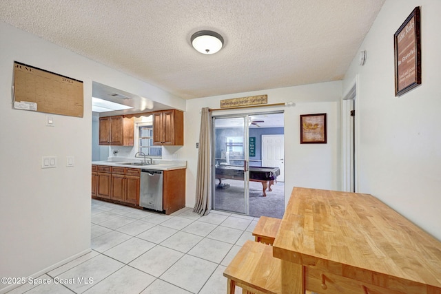 1216 Cannon St, Melbourne, FL 32935 - kitchen with dishwasher, light countertops, a textured ceiling, light tile patterned floors, and brown cabinets
