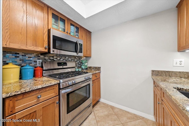 2975 Matthew Dr, Rockledge, FL 32955 - kitchen with appliances with stainless steel finishes, tasteful backsplash, light stone countertops, and glass insert cabinets