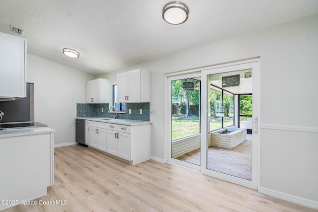 1384 Vancouver Ave SE, Palm Bay, FL 32909 - kitchen with dishwasher, white cabinets, light countertops, light wood-type flooring, and decorative backsplash