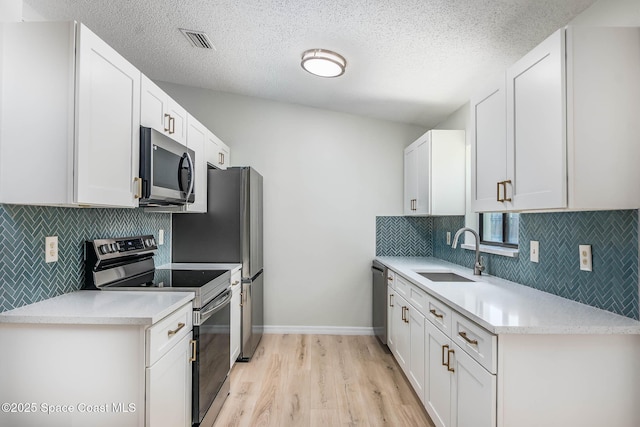 1384 Vancouver Ave SE, Palm Bay, FL 32909 - kitchen with appliances with stainless steel finishes, light wood finished floors, light countertops, white cabinets, and a textured ceiling