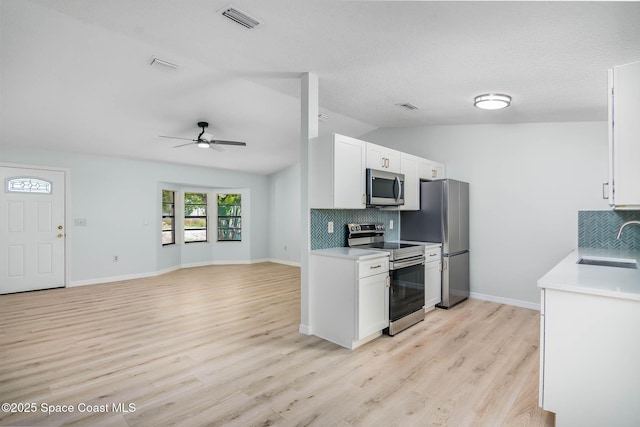 1384 Vancouver Ave SE, Palm Bay, FL 32909 - kitchen with stainless steel appliances, lofted ceiling, backsplash, ceiling fan, and white cabinets