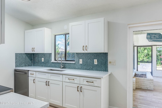 1384 Vancouver Ave SE, Palm Bay, FL 32909 - kitchen with stainless steel dishwasher, light countertops, white cabinetry, and decorative backsplash