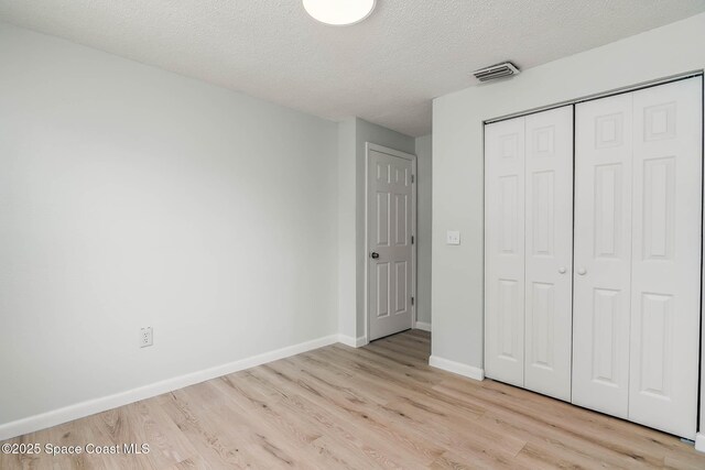1384 Vancouver Ave SE, Palm Bay, FL 32909 - unfurnished bedroom featuring light wood finished floors, a textured ceiling, and a closet