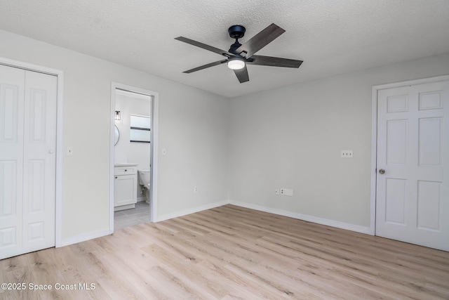1384 Vancouver Ave SE, Palm Bay, FL 32909 - unfurnished bedroom with light wood-style floors, a closet, a textured ceiling, ensuite bathroom, and ceiling fan