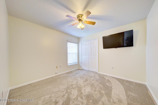 6980 Cairo Rd, Cocoa, FL 32927 - unfurnished bedroom featuring carpet flooring, a closet, a textured ceiling, and a ceiling fan