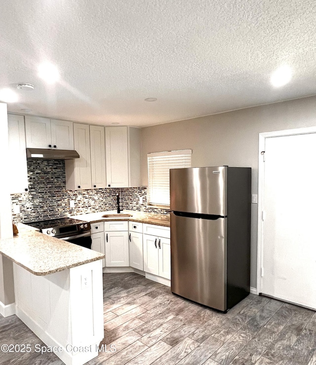 5600 N Banana River Blvd Unit 38, Cocoa Beach, FL 32931 - kitchen with appliances with stainless steel finishes, a textured ceiling, a peninsula, backsplash, and wood finished floors