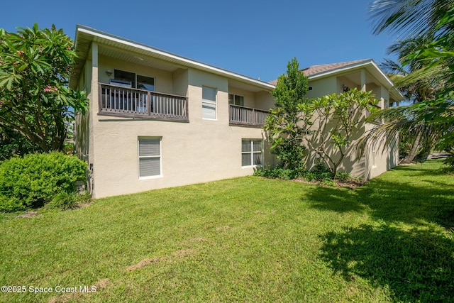 105 Ocean View Ln, Melbourne, FL 32903 - rear view of house featuring stucco siding, a balcony, and a yard