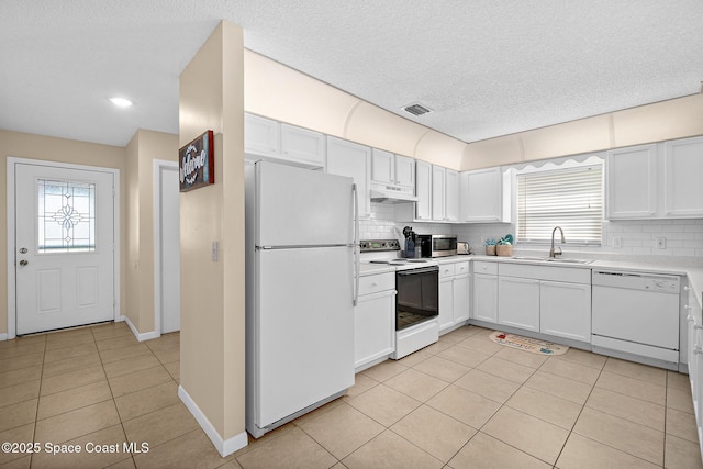 147 Ocean View Ln, Melbourne, FL 32903 - kitchen with white appliances, under cabinet range hood, light tile patterned floors, decorative backsplash, and a textured ceiling