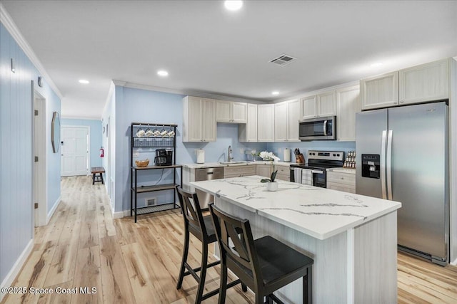 513 Ronnie Dr, Indian Harbour Beach, FL 32937 - kitchen with stainless steel appliances, crown molding, a kitchen bar, a kitchen island, and light wood-type flooring