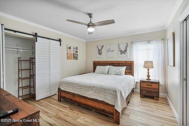 513 Ronnie Dr, Indian Harbour Beach, FL 32937 - bedroom featuring a barn door, light wood finished floors, ornamental molding, a textured ceiling, and a ceiling fan