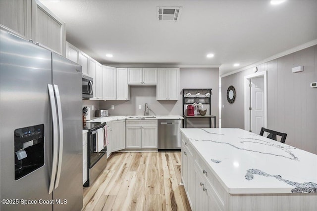 513 Ronnie Dr, Indian Harbour Beach, FL 32937 - kitchen with stainless steel appliances, ornamental molding, light wood-type flooring, a center island, and light stone counters