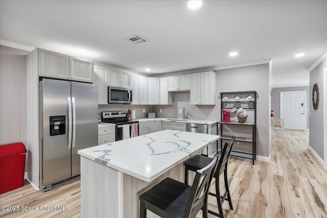 513 Ronnie Dr, Indian Harbour Beach, FL 32937 - kitchen featuring stainless steel appliances, ornamental molding, a kitchen island, light wood-style flooring, and a breakfast bar area