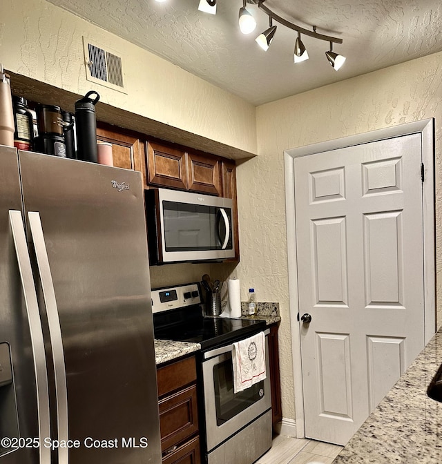2190 Forest Knoll Dr NE Unit 90-202, Palm Bay, FL 32905 - kitchen featuring stainless steel appliances, a textured wall, a textured ceiling, and light stone countertops