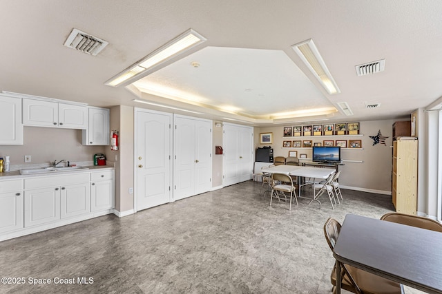 3360 S Atlantic Ave Unit 212, Cocoa Beach, FL 32931 - kitchen featuring tile patterned floors, a tray ceiling, white cabinetry, light countertops, and a desk