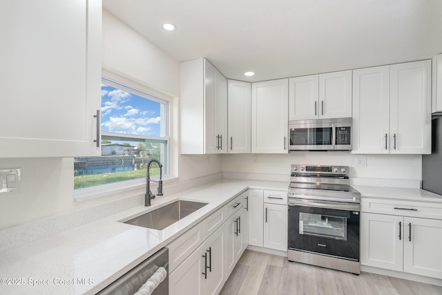 320 Alabama Ave, Merritt Island, FL 32953 - kitchen with stainless steel appliances, white cabinets, recessed lighting, and light wood-style flooring