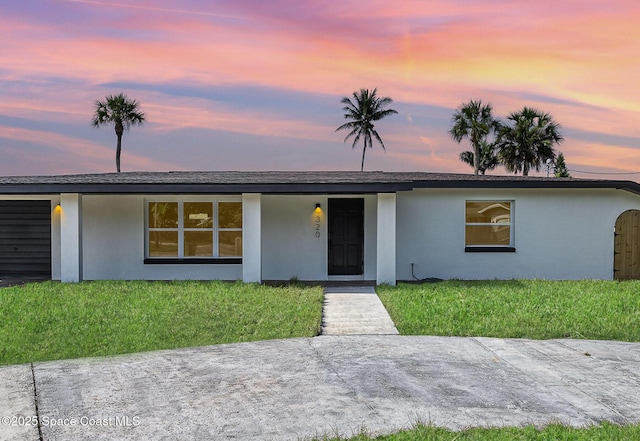 320 Alabama Ave, Merritt Island, FL 32953 - view of front of house with stucco siding, a lawn, and an attached garage