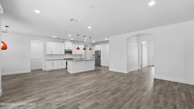 3110 Addison Dr, Melbourne, FL 32940 - kitchen with open floor plan, appliances with stainless steel finishes, arched walkways, light wood-style floors, and recessed lighting