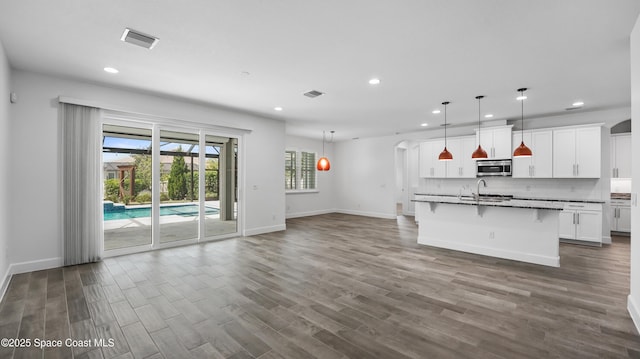 3110 Addison Dr, Melbourne, FL 32940 - kitchen with stainless steel microwave, recessed lighting, dark wood-type flooring, a breakfast bar, and white cabinets