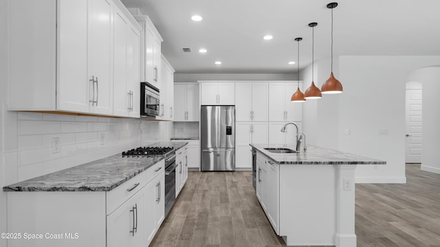3110 Addison Dr, Melbourne, FL 32940 - kitchen featuring appliances with stainless steel finishes, light wood-style floors, arched walkways, recessed lighting, and backsplash