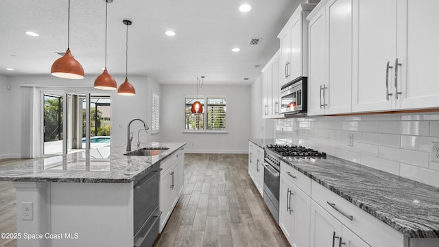 3110 Addison Dr, Melbourne, FL 32940 - kitchen featuring appliances with stainless steel finishes, recessed lighting, light wood-type flooring, tasteful backsplash, and a center island with sink