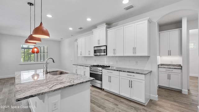 3110 Addison Dr, Melbourne, FL 32940 - kitchen featuring stainless steel appliances, arched walkways, recessed lighting, white cabinets, and light wood-style floors