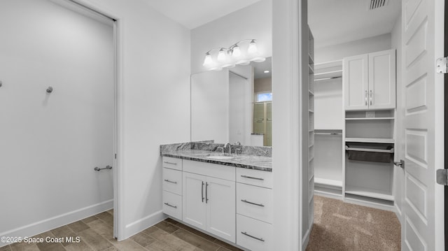 3110 Addison Dr, Melbourne, FL 32940 - bathroom featuring vanity, a walk in closet, and wood finished floors