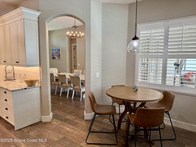 4569 Chastain Dr, Melbourne, FL 32940 - dining area featuring a textured wall, light wood finished floors, arched walkways, and a chandelier