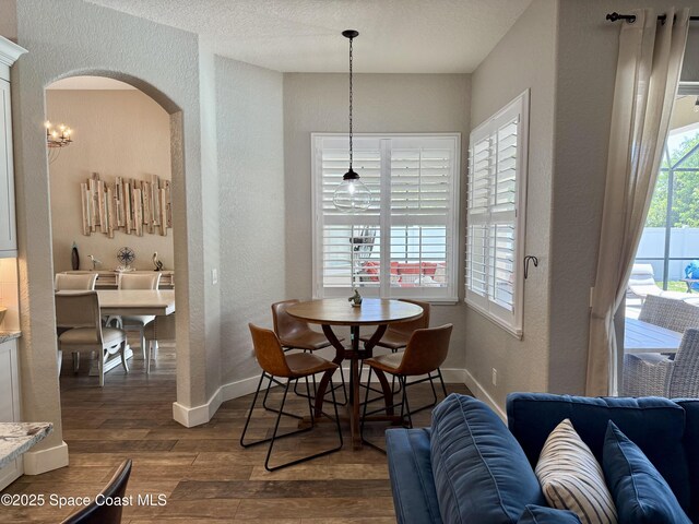 4569 Chastain Dr, Melbourne, FL 32940 - dining area featuring a textured wall, dark wood-style floors, and arched walkways