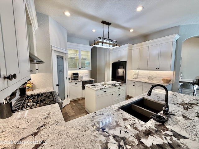 4569 Chastain Dr, Melbourne, FL 32940 - kitchen featuring refrigerator, wood finished floors, decorative backsplash, arched walkways, and light stone countertops