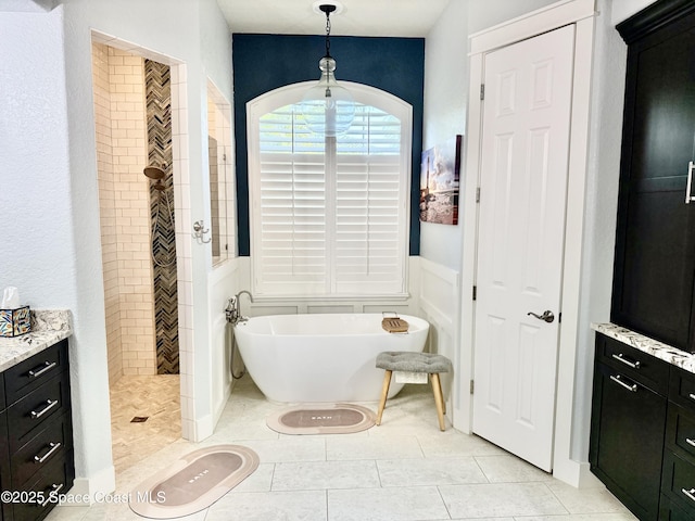 4569 Chastain Dr, Melbourne, FL 32940 - full bathroom with a freestanding tub, tiled shower, tile patterned flooring, vanity, and a wainscoted wall