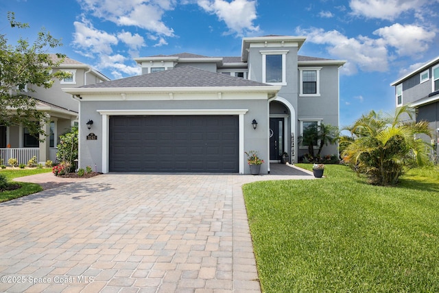 3243 Casare Dr, Melbourne, FL 32940 - view of front of home with a front yard, stucco siding, decorative driveway, an attached garage, and roof with shingles