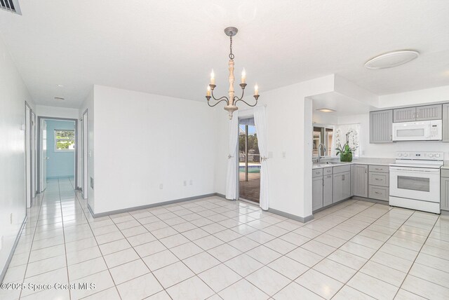 55 Yacht Haven Dr, Cocoa Beach, FL 32931 - kitchen with white appliances, gray cabinetry, light countertops, a chandelier, and light tile patterned floors