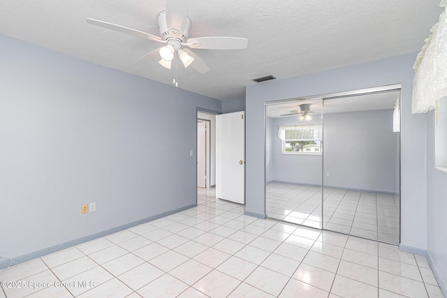 55 Yacht Haven Dr, Cocoa Beach, FL 32931 - unfurnished bedroom featuring a closet, light tile patterned floors, ceiling fan, and a textured ceiling
