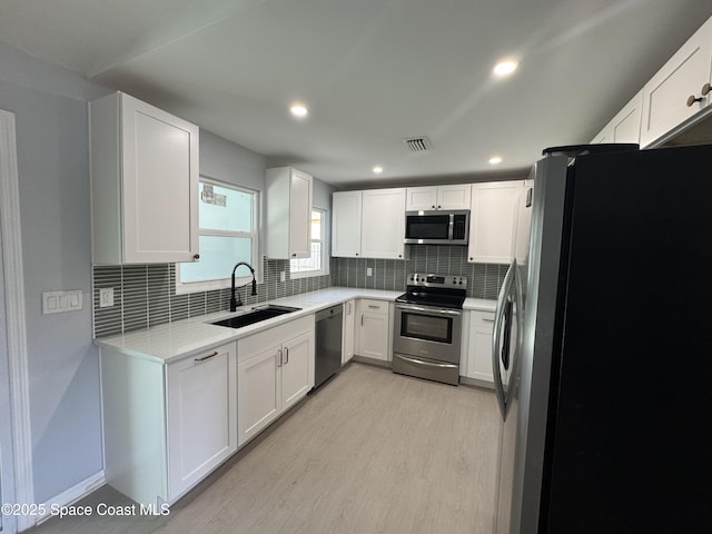 669 Vocelle Ave, Sebastian, FL 32958 - kitchen with stainless steel appliances, tasteful backsplash, light wood-style floors, white cabinets, and recessed lighting