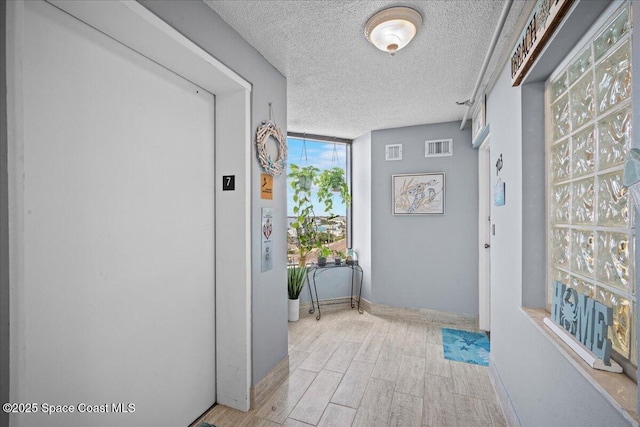 3221 S Atlantic Ave Unit 703, Cocoa Beach, FL 32931 - corridor featuring elevator, light wood finished floors, and a textured ceiling