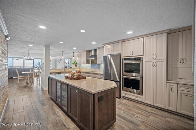 3221 S Atlantic Ave Unit 703, Cocoa Beach, FL 32931 - kitchen featuring stainless steel appliances, wall chimney range hood, light wood-style flooring, recessed lighting, and a textured ceiling