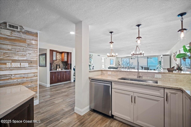 3221 S Atlantic Ave Unit 703, Cocoa Beach, FL 32931 - kitchen with stainless steel dishwasher, a chandelier, wood finished floors, light stone countertops, and a textured ceiling