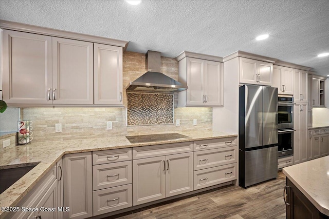 3221 S Atlantic Ave Unit 703, Cocoa Beach, FL 32931 - kitchen with appliances with stainless steel finishes, wall chimney exhaust hood, wood finished floors, a textured ceiling, and light stone counters
