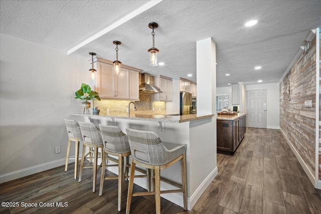 3221 S Atlantic Ave Unit 703, Cocoa Beach, FL 32931 - kitchen featuring wall chimney exhaust hood, a peninsula, refrigerator, backsplash, and dark wood-style floors