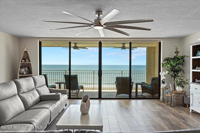 3221 S Atlantic Ave Unit 703, Cocoa Beach, FL 32931 - living area featuring floor to ceiling windows, a ceiling fan, wood finished floors, a textured ceiling, and a water view
