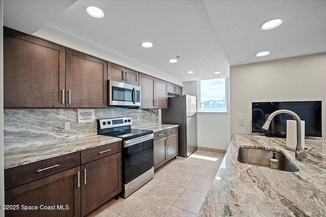 3221 S Atlantic Ave Unit 703, Cocoa Beach, FL 32931 - kitchen featuring stainless steel appliances, tasteful backsplash, light tile patterned flooring, light stone counters, and recessed lighting