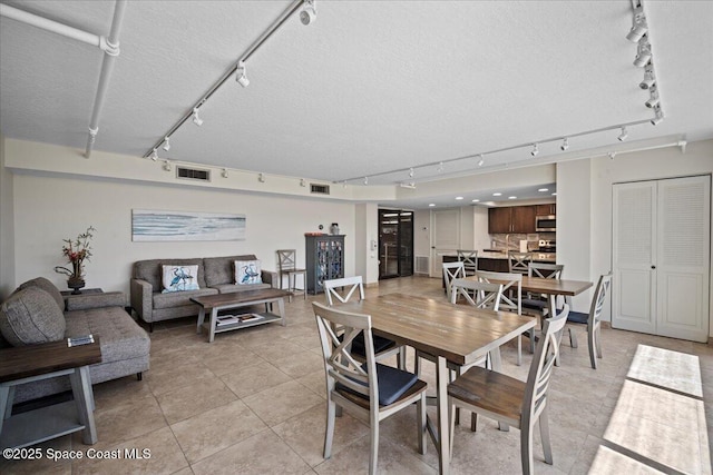 3221 S Atlantic Ave Unit 703, Cocoa Beach, FL 32931 - dining area with rail lighting, a textured ceiling, and light tile patterned floors