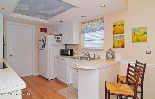 1310 SW 9th Ter, Boca Raton, FL 33428 - kitchen with white appliances, a raised ceiling, light wood finished floors, light countertops, and a peninsula